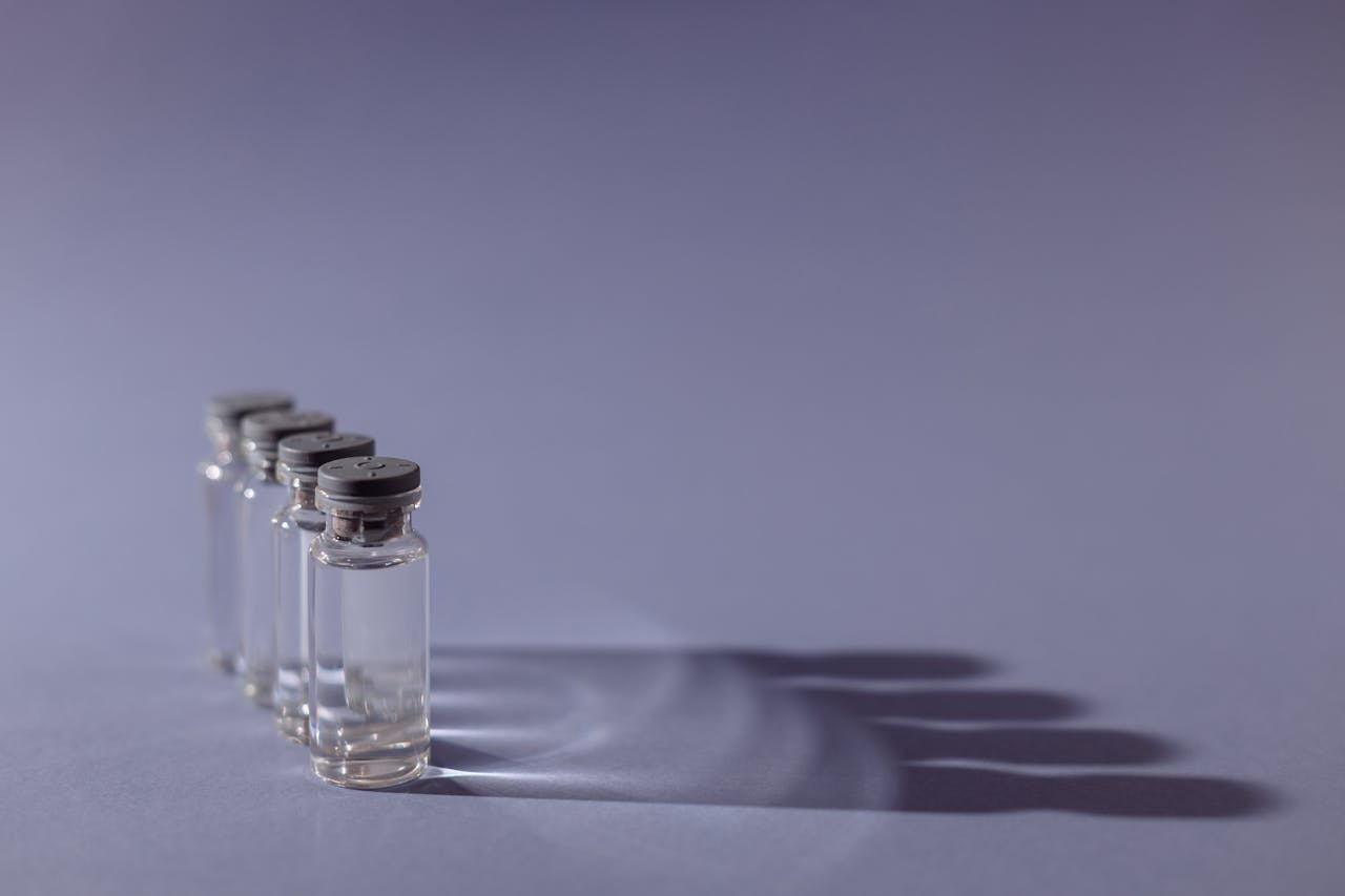 Close-up of lined up vaccine vials casting shadows, symbolizing medical advancements and health.
